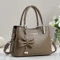 Detail of brown litchi pattern leather handbag with pearl bow charm and metal buckle - Brown