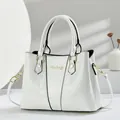 Detail of white handbag featuring crocodile texture, smooth lacquer, and gold hardware - White