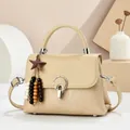 Detail of beige flap handbag with vertical textures and gold circular metal lock - Apricot