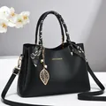 Elegante schwarze Handtasche aus Leder mit dekorativem Seidenschal und goldenem Anhänger - Schwarz