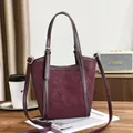 Elegante burgunderrote Tragetasche mit matter Textur und Golddetails auf dem Tisch - Rot