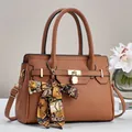 Detail of lychee textured leather tote with gold hardware and silk scarf on handle - Earthy Yellow