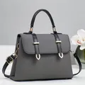 Detail of grey twill texture and black leather strap with gold hardware on a handbag - Black