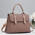 Detail view of the brown textured fabric handbag featuring gold buckles and elegant leather straps - Brown