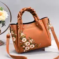 Caramel brown handbag with floral embroidery and braided handle in a premium crossbody style - Earthy Yellow