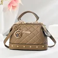 Brown quilted pillow handbag with golden metal frame and rivets on white podium - Khaki