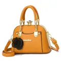 Close-up of yellow shell-shaped handbag with golden metal frame and diamond clasp detail - Khaki/Earth Yellow