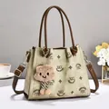 Detail der Vintage-Monogramm-Tasche mit Lederriemen und einem Plüschwolken-Anhänger - 24x10x20cm / Grün