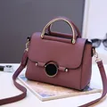 Sac à main carré violet en cuir grainé avec poignée dorée et bandoulière sur le bureau - Violet