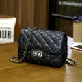 Classic black quilted leather chain bag with metallic studs on a wooden cafe table - Black
