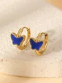 Détail de créoles dorées avec papillon en émail bleu posées sur un support en pierre - Bleu