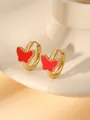 Detail of elegant gold butterfly hoop earrings with vibrant red inlay on beige ceramic - Red