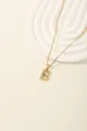 Macro detail of golden letter B pendant with blue zircon and radial texture on o-chain - Letter B