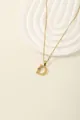 Detail of gold letter D pendant with radial texture and sparkling colored zircons - Letter D