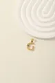 Detail view of a gold-plated letter G pendant with radial texture and inlaid gemstones - Letter G