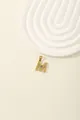Detail of gold letter M pendant with blue gemstone and cubic zirconia accents - M