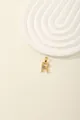 Macro view of a gold-plated letter R pendant with blue and white zircons on white steps - Letter R