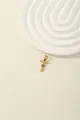 Detail of a gold cross pendant with radiant texture and inlaid blue and white zircons - Letter T