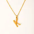 Close-up of golden K-letter pendant with natural bamboo texture on a fine chain - Letter K