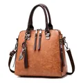 Classic brown PU leather handbag with cat pendant and fringe zippers on white background - Earthy Yellow