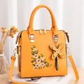 Orange embroidered floral handbag with a butterfly charm and removable shoulder strap - Yellow