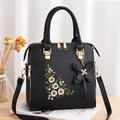 Elegante borsa nera con ricami floreali e accessorio pendente a forma di farfalla - Nero