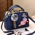 Navy blue faux leather handbag with floral accents and pompom keychain on marble - Sapphire Blue