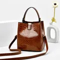 Dunkelbraune Eimer-Tasche aus Kunstleder mit Krokoprägung und goldfarbenen Details - Erdgelb