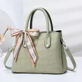 Detail of mint green crocodile embossed tote bag featuring elegant silk scarf handle decoration - Green
