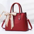 Detail of burgundy crocodile pattern handbag with elegant silk scarf and silver hardware - Red
