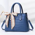 Detailed close-up of blue stone pattern leather bag with decorative silk scarf and silver hardware - Blue
