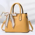 Detail of yellow stone-pattern handbag with elegant silk scarf and CSGW logo - Yellow