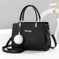 Elegante bolso de mano en cuero sintético negro con logo metálico y pompón de pelo blanco - Negro