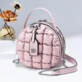 Rosa gesteppte runde Handtasche mit Kettenschultergurt und Kleeblatt-Anhänger im Studio - Hellrosa