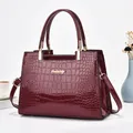 Détails du sac à main en cuir verni bordeaux à motif crocodile et finitions dorées - Bordeaux