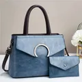 Detalle del juego de bolsos de cuero sintético azul con hebilla plateada y asas marrones - Azul Oro / Conjunto De Bolso De Mano Azul De Piel Sintética Estilo Vintage Diseño De Solapa Tipo Sobre Herrajes De Metal Plateado Asas De Color Marrón Oscuro.