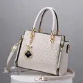 Beige Tragetasche mit geometrischer Prägung, goldenen Details und Kleeblatt-Anhänger - Gebrochenes Weiß