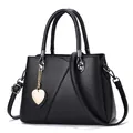 Klassische schwarze Handtasche mit Lederstruktur, goldenem Herzanhänger und Schultergurt - Schwarz