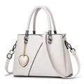 Elegante bolso de mano en cuero blanco crema con detalles negros y colgante de corazón - Blanco