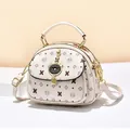 Creamy white printed handbag with cartoon cat charm and detachable shoulder strap - Off White