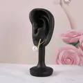 Boucle d'oreille dorée en X avec zircons et perle blanche sur un support d'exposition - 10*4*3.5CM / Noir