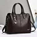 Detail einer dunkelbraunen Handtasche aus Leder mit Perlenanhänger und Metallbeschlägen - Kaffeebraun