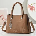 Detail view of brown textured tote bag featuring a leaf pendant and pearl charm - Dark Khaki