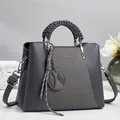 Vue macro des coutures en cuir gris et de la poignée tressée d'un sac à main chic - Gris