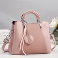Sac à main bandoulière rose avec anses tressées et pendentif boule en studio - Rose