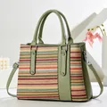 Detail of woven straw tote bag with olive green leather trim and vertical stud accents - Striped Pattern / Green