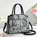 Elegante schwarz-weiße Tote-Bag mit Ledergriffen und goldfarbenen Metallbeschlägen - Schwarz