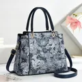 Detail of navy blue handbag featuring white floral embroidery and gold metal hardware - 27x12x22cm / Blue