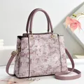 Elegante malvenfarbene Handtasche mit floraler Spitze und goldenen Metallbeschlägen - Lila