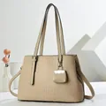 Beige faux crocodile skin tote bag with matching mini pendant on a minimalist background - Khaki